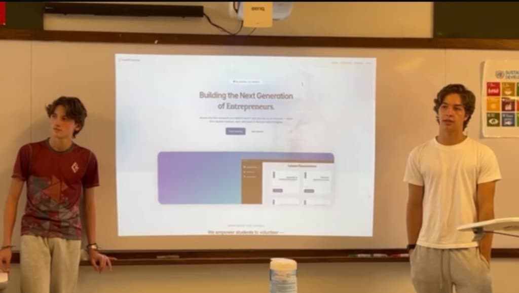 Two student mentors presenting RootED futures curriculum on a classroom projector screen